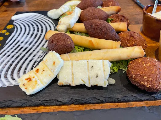 Assorted fried pastries and breaded items arranged on a slate platter with striped napkins, ready to serve.