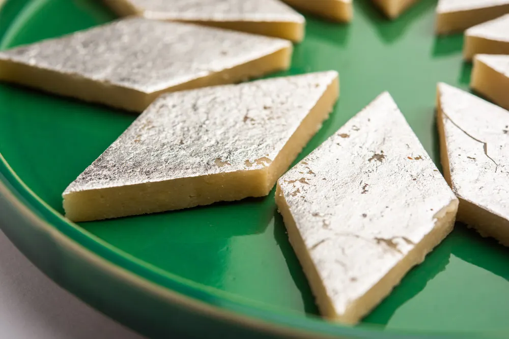 Sliced shortbread biscuits dusted with icing sugar arranged on a green plate.