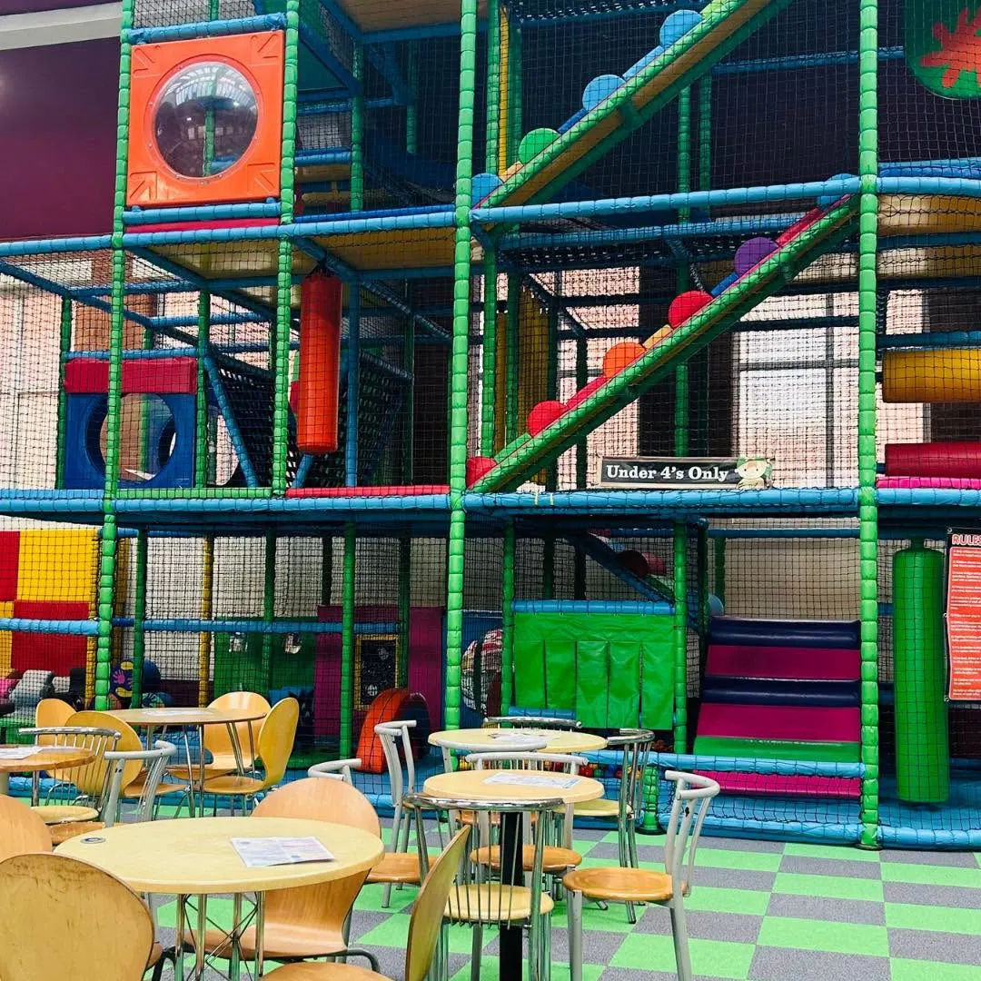 Under-4s soft-play frame with padded climbers, cafe seating and green check floor