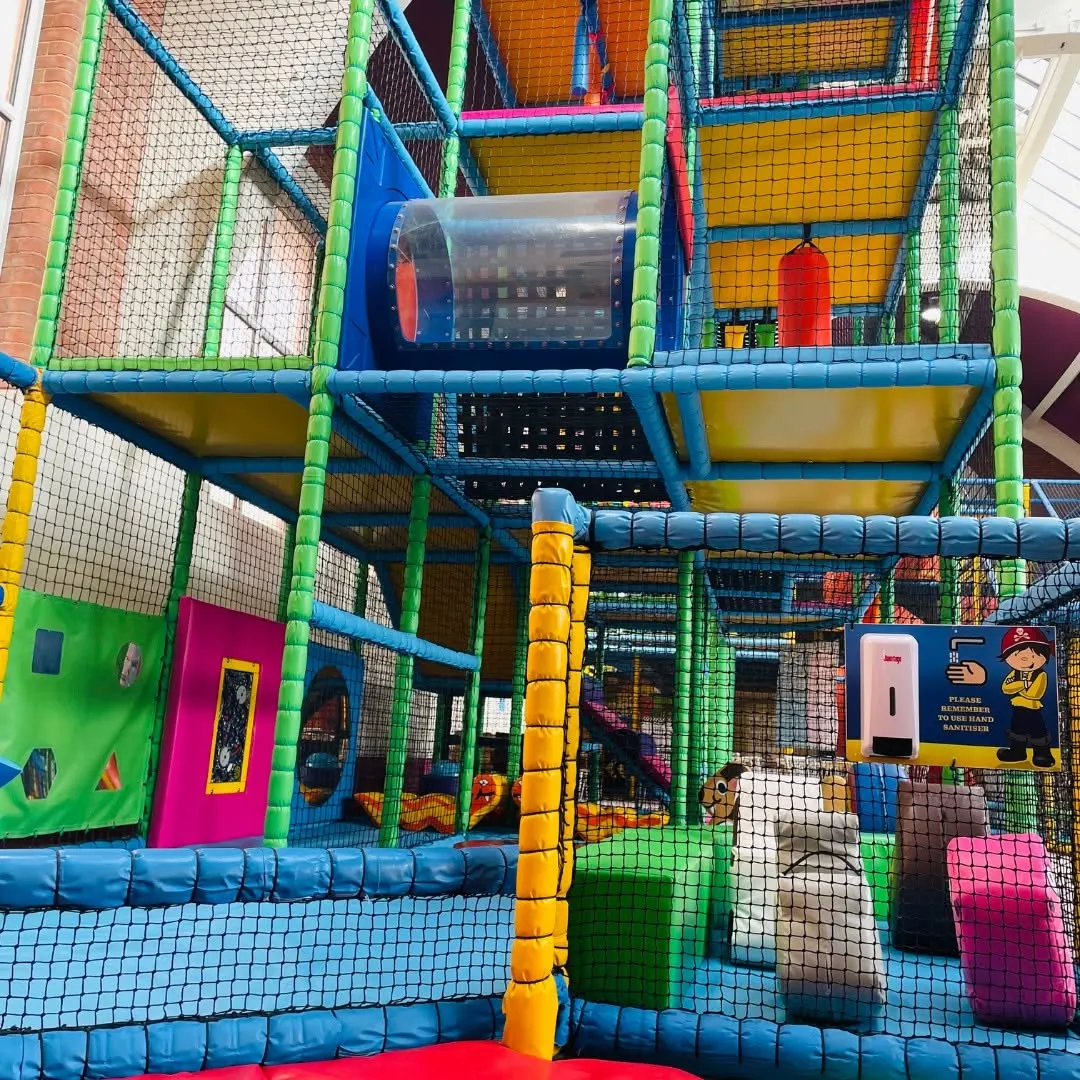 Close-up of multi-level soft-play frame with green and blue padding and pirate hand-sanitiser sign