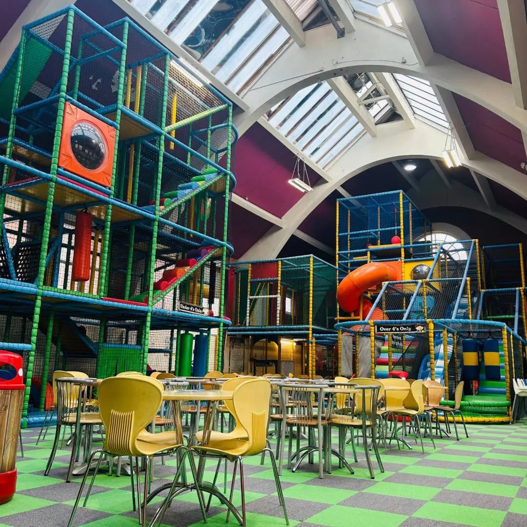 Multi-storey soft-play frames for under-4s and over-4s with cafe tables and green check floor